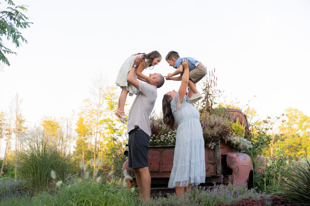 Mom and Dad holding their kids in the air and being fun together during a family photography session with MelMarie Photography in West Bend Wisconsin