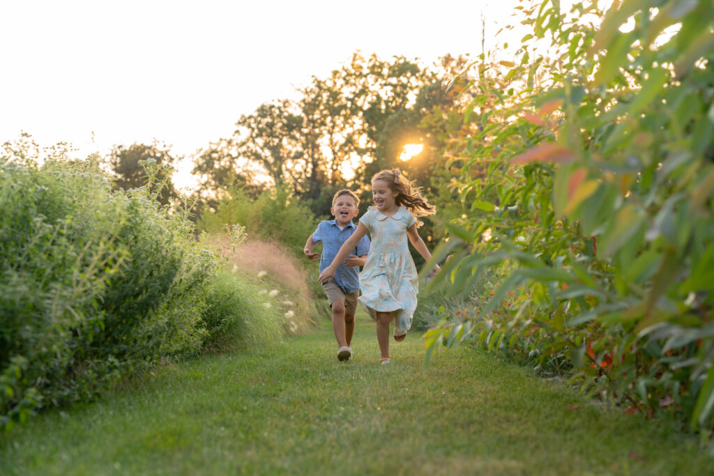 Kids running through flower field with MelMarie Photography during a family photography session in West Bend Wisconsin