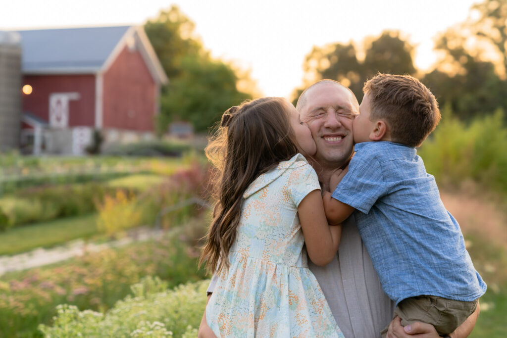 Kids kissing their dad on the cheek during a family photography session with MelMarie Photography in West Bend Wisconsin