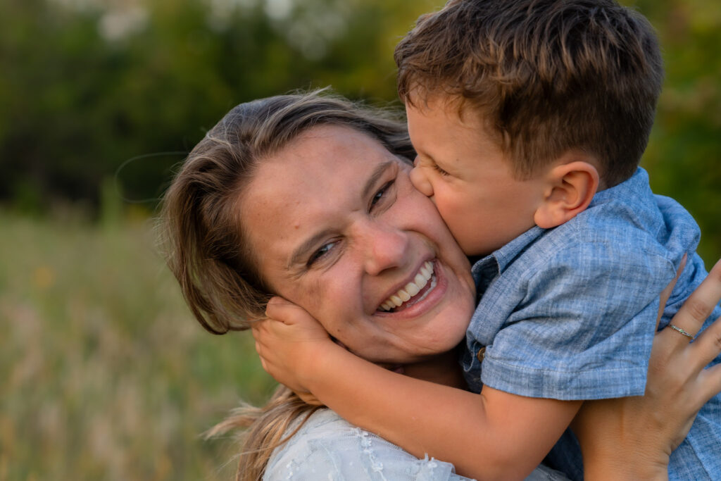 Boy kissing Mom on the cheek with MelMarie Photography during a family photography session in West Bend Wisconsin