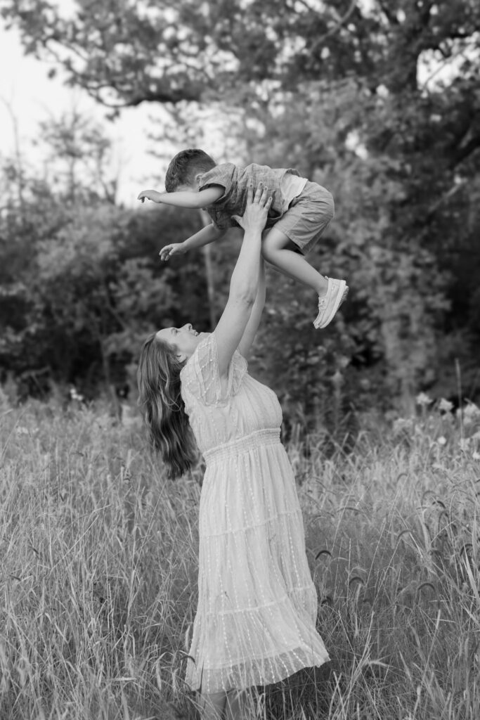 Mom throwing son in the air during a family photography session with MelMarie Photography in West Bend Wisconsin