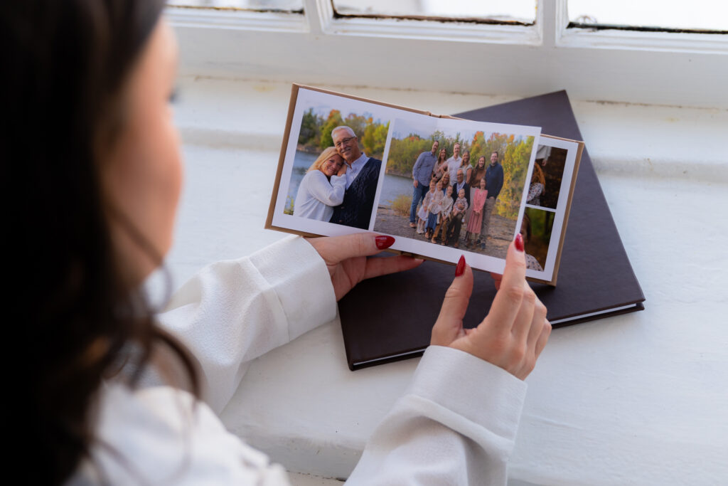 Brunette girl with red nails looking through a photo album of her family in Cedarburg, Wisconsin