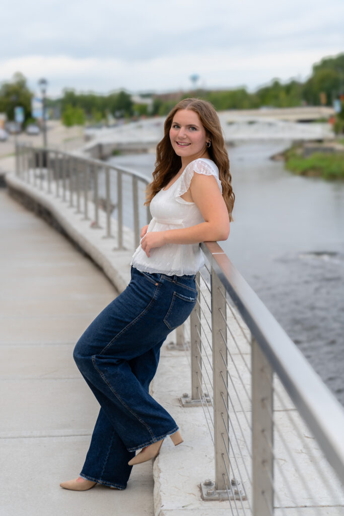 Young woman leaning up against fence looking at camera