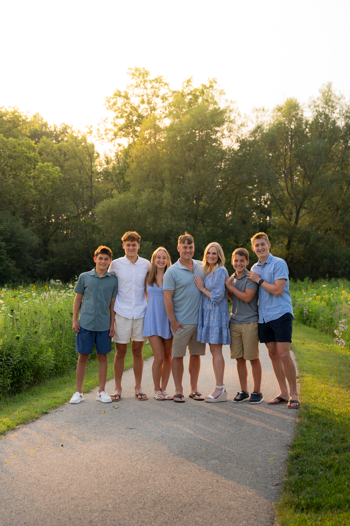 Smiling family looking at the camera wearing blue at the park in West Bend