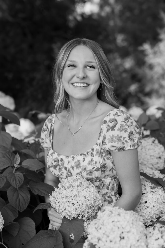 Young girl smiling while standing in a bunch of flowers