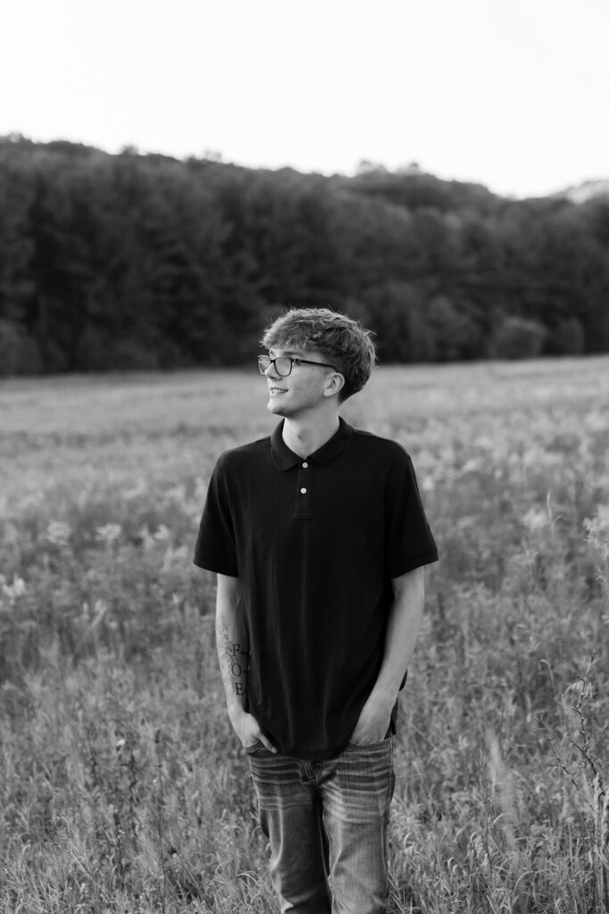 Boy standing in field with hands in his pockets