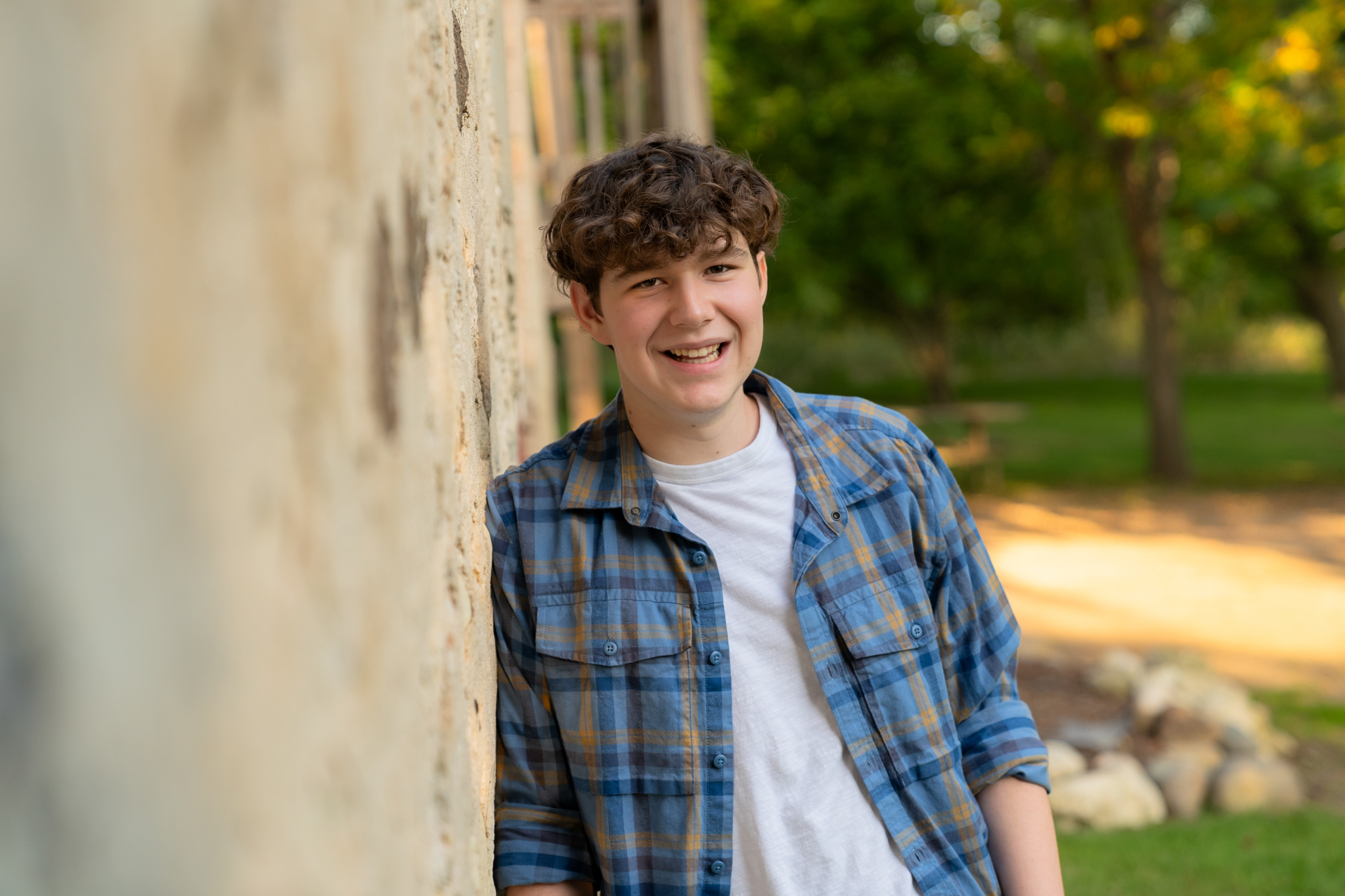 Senior boy smiling at the camera while leaning against the wall