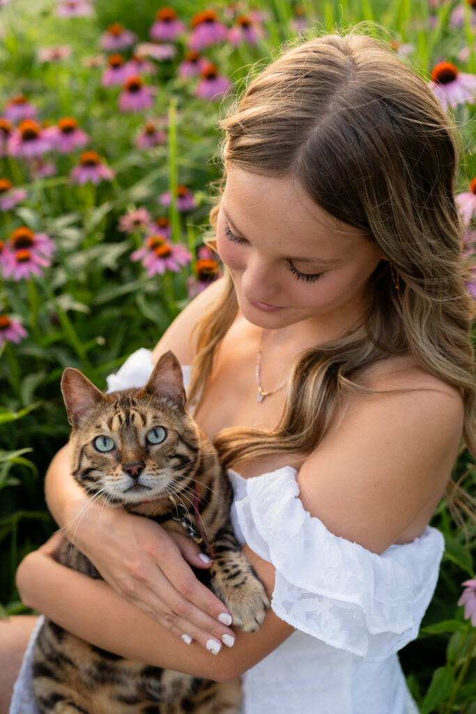Senior girl holding her cat in coneflowers
