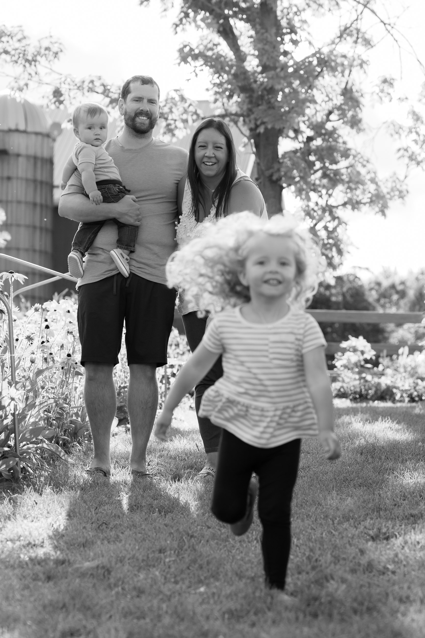 Family laughing while their daughter is running toward photographer
