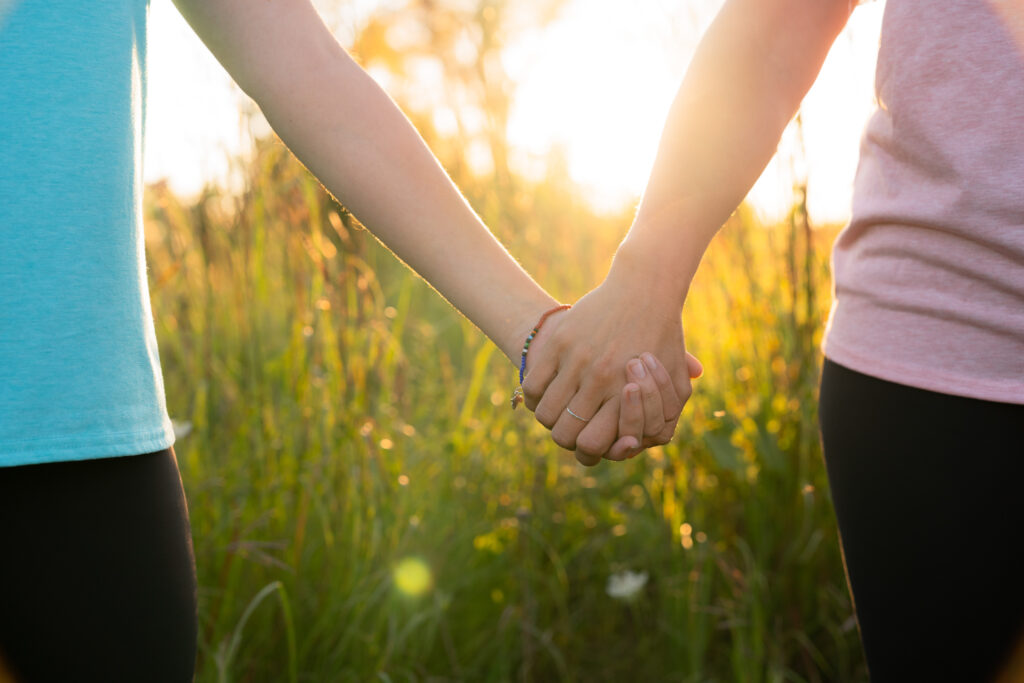 Mom and daughter holding hands with sunset in the background