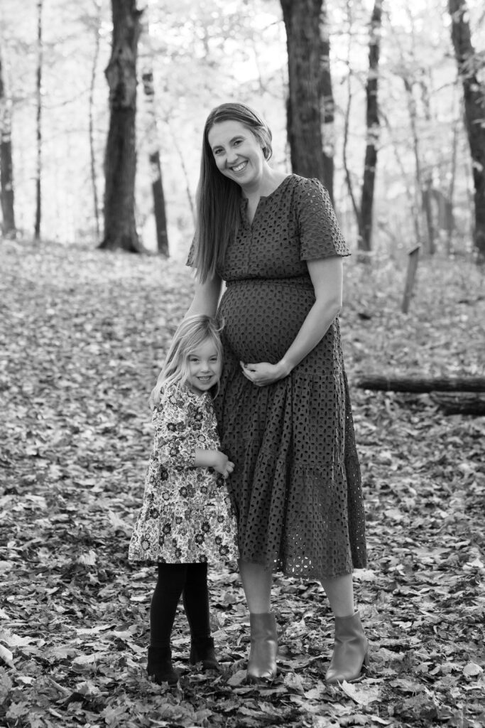 Mom holding her pregnant belly and her daughter during a maternity photography session in Menomonee Falls Wisconsin