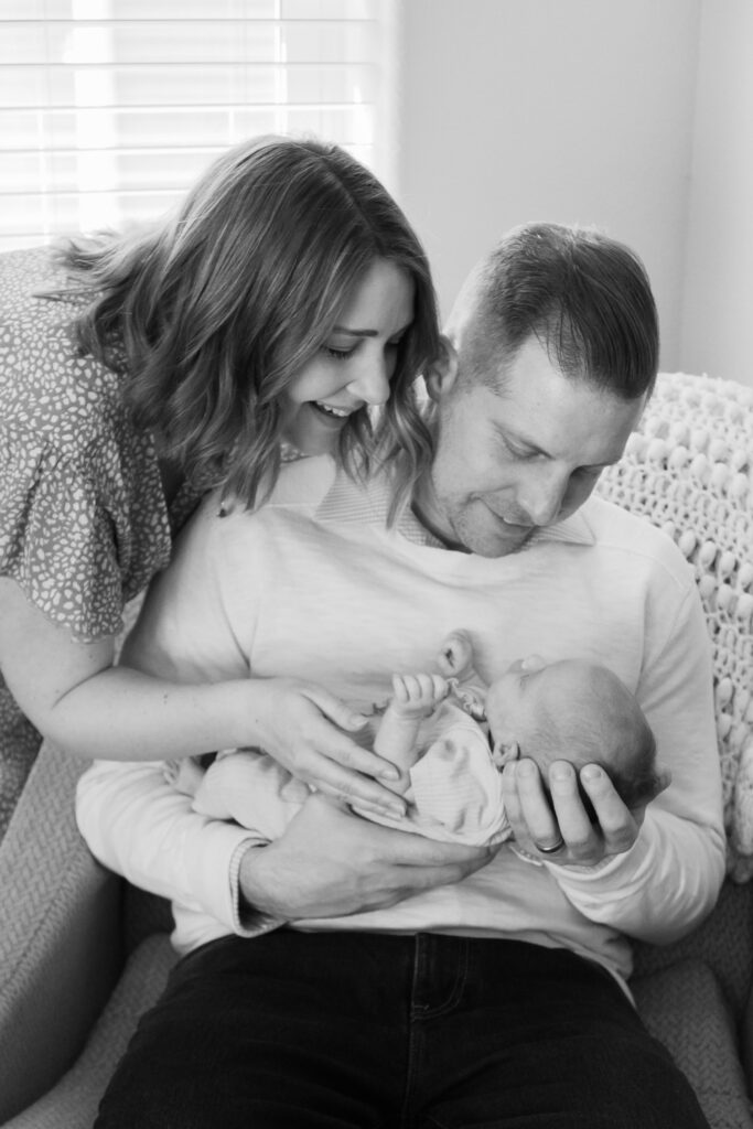 Parents holding their newborn baby together in their home, captured during a cozy Menomonee Falls in-home newborn session