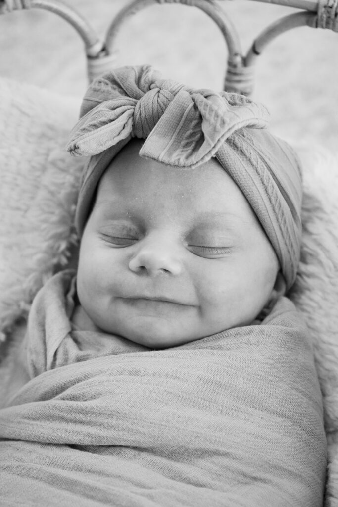 Smiling newborn baby’s face captured while swaddled during a West Bend in-home newborn photography session