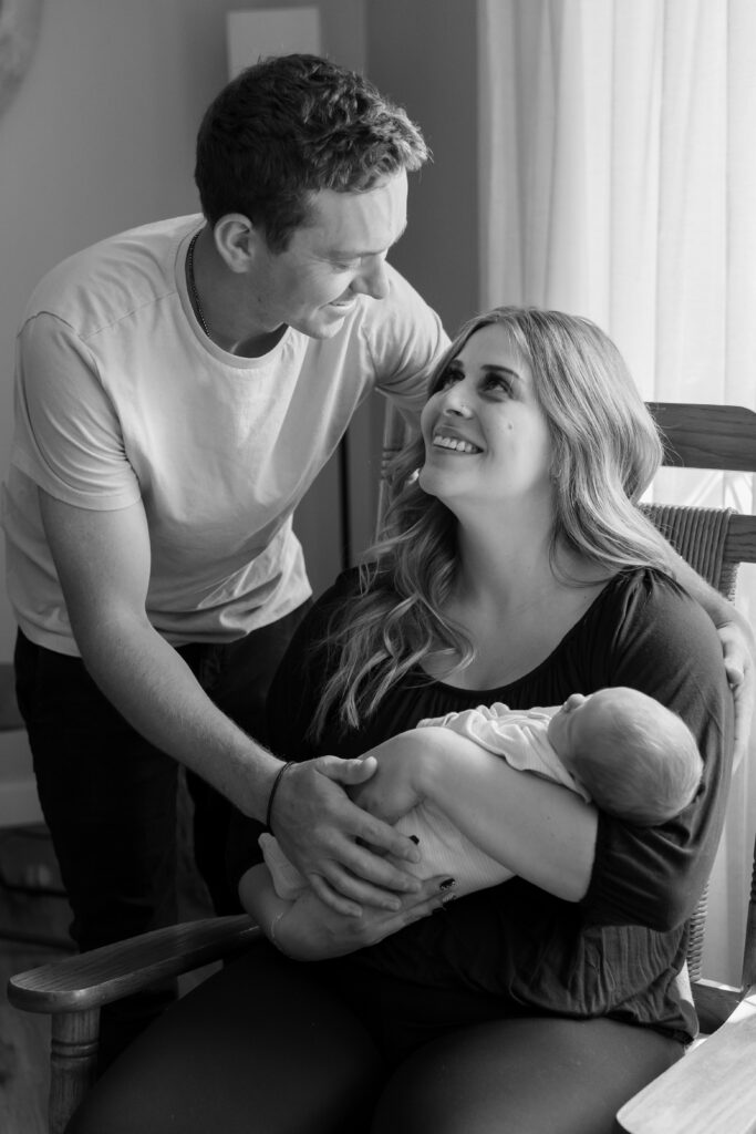 Mom and dad holding their newborn baby and smiling at each other
