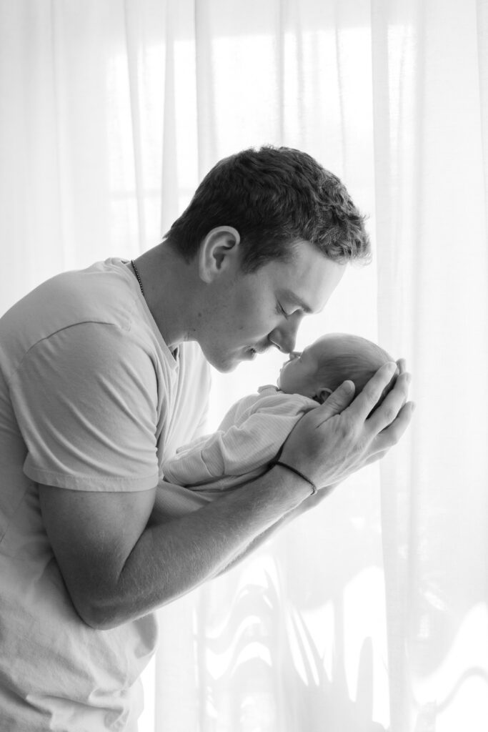 Father cradling his newborn baby during an in-home newborn photography session in Menomonee Falls
