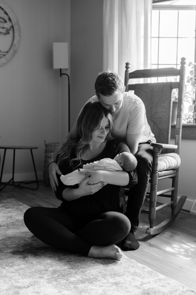 Parents holding their newborn baby together in their home, captured during a cozy Menomonee Falls in-home newborn session