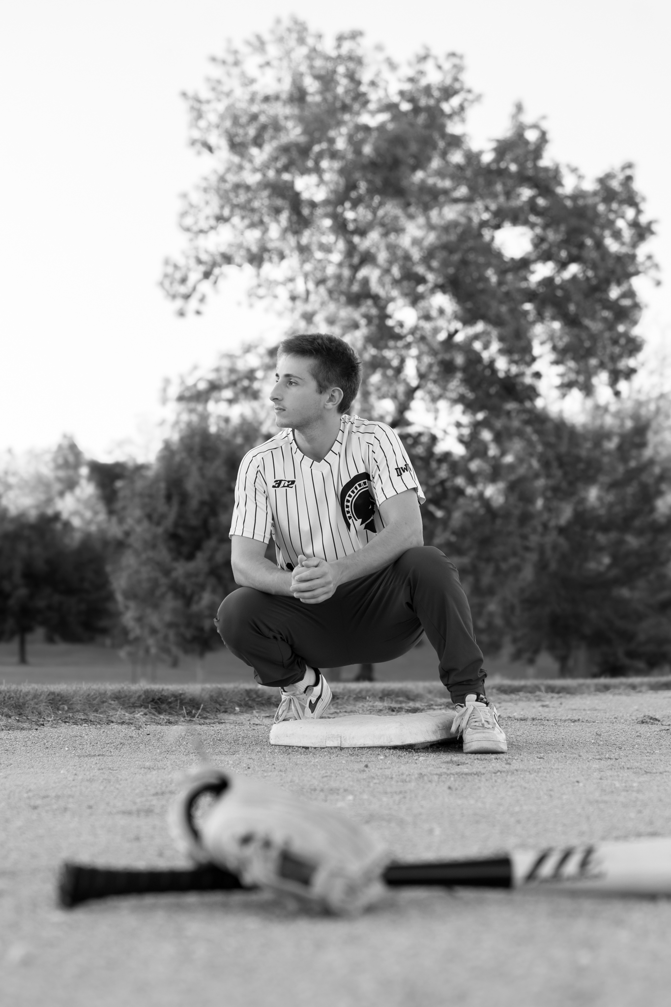 Brookfield Central High school Wisconsin senior baseball player squatting near base with baseball and mit in foreground of photo