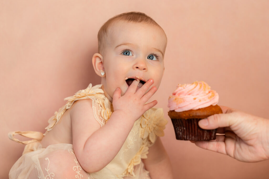 Sweet first birthday photo with cake and tiny hands