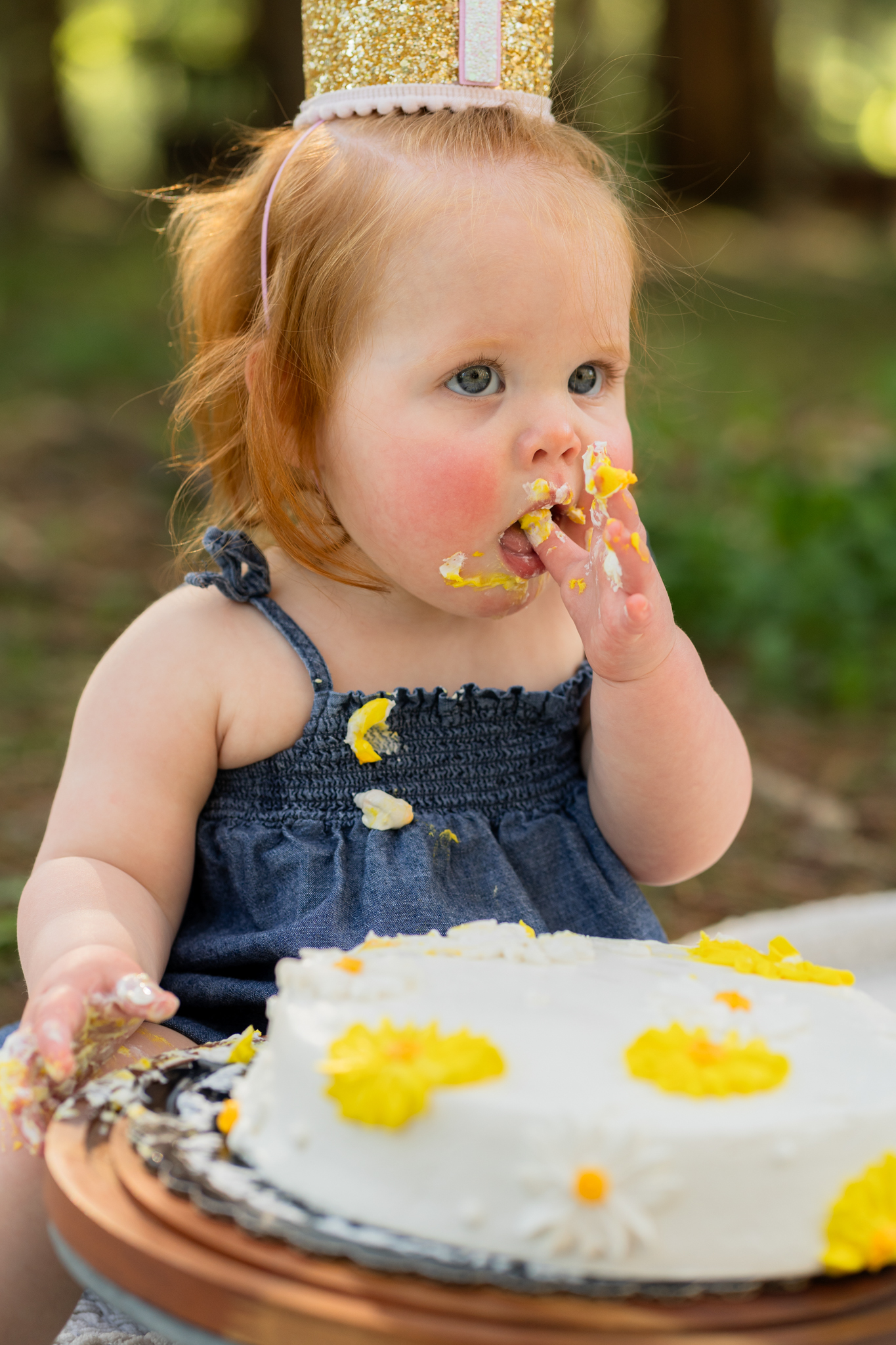 Smiling one-year-old with frosting on their face during cake smash