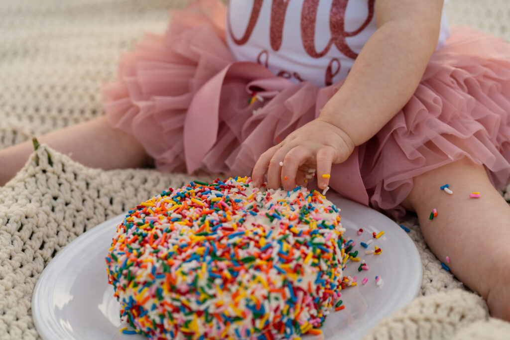 One-year-old reaching for frosting at a cake smash photoshoot