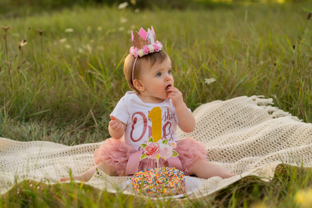 Curious toddler exploring cake during a milestone session