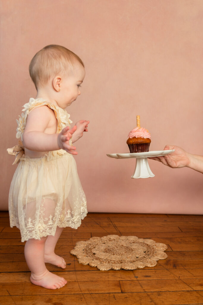 Little girl seeing her cupcake for first time during one year milestone photos in studio