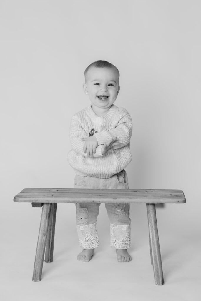 Smiling one year old crossing her arms and looking directly at the camera during photography session