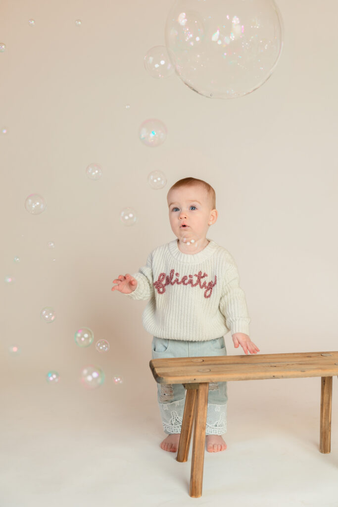 Felicity looking at bubbles in studio for her one-year milestone session in Cedarburg, photographed by West Bend photographer