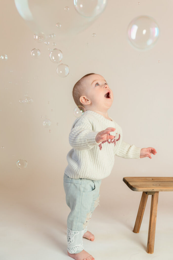 Little girl reaching for bubbles during her one-year studio session in Cedarburg, photographed by West Bend family photographer
