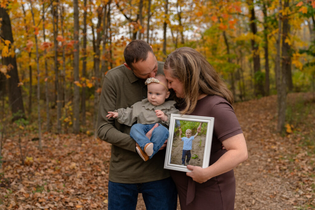 Mom and dad holding their daughter in their arms and nuzzling her softly with their noses during a fall mini session in Menomonee Falls, Wisconsin