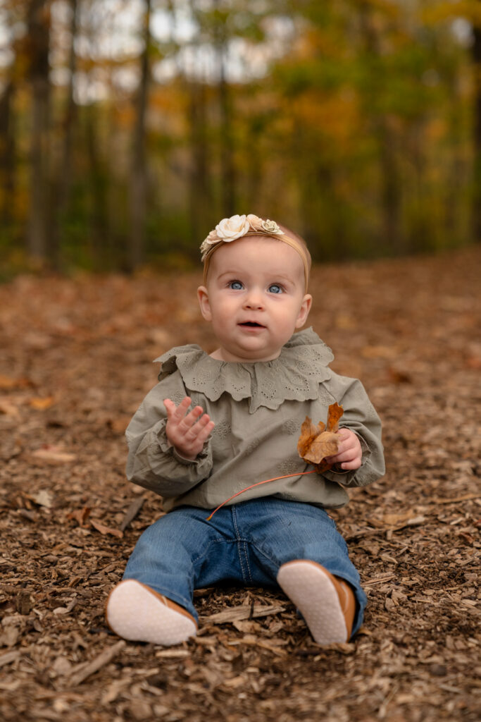 Toddler portrait in fall leaves during family photos in Menomonee Falls