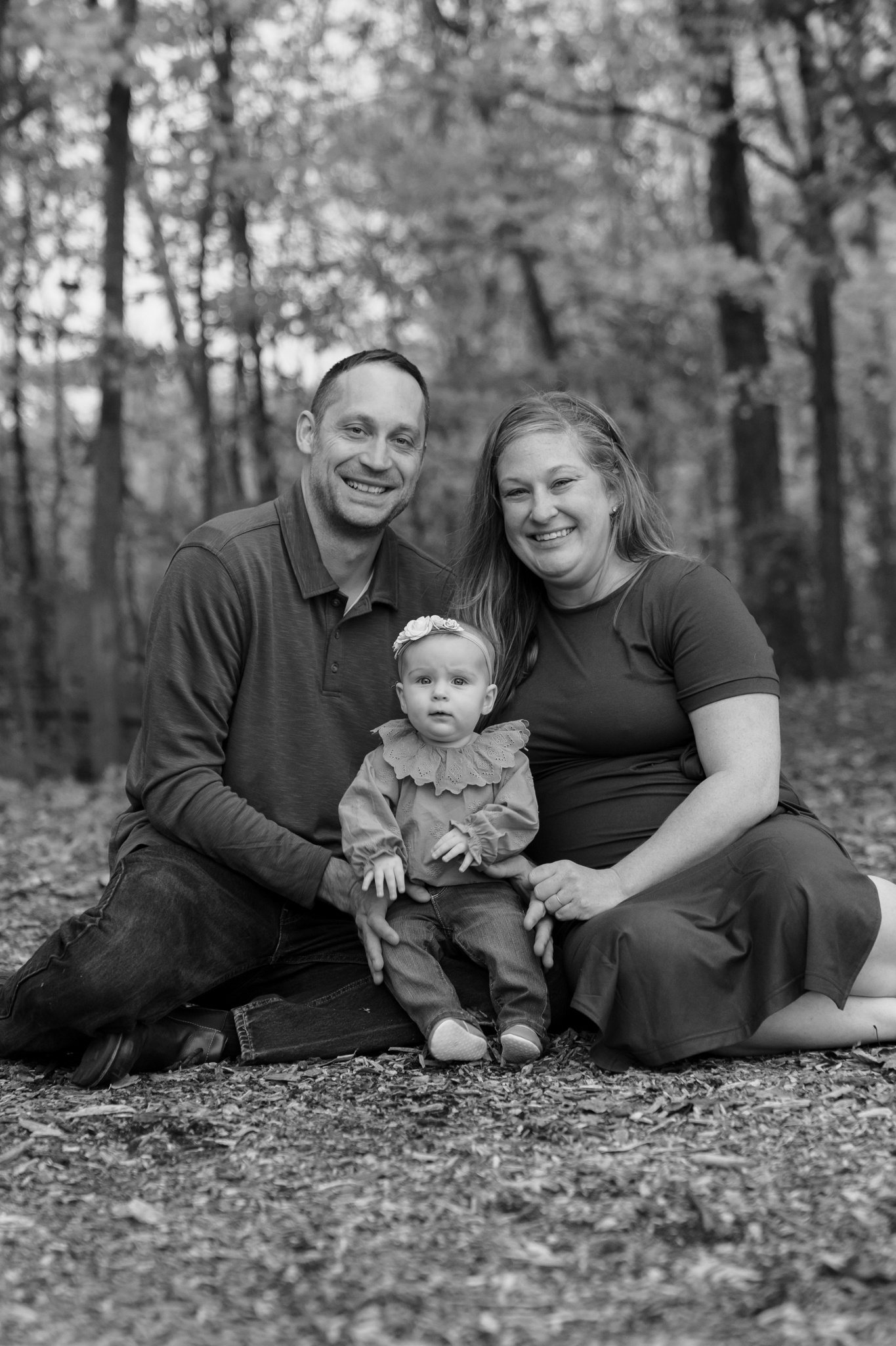 Family cuddling on ground and smiling at the camera during golden hour session at Menomonee Park Wisconsin