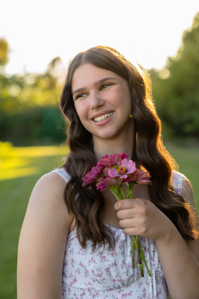 Young girl holding flower from Lannon sunflower farm and smiling during senior photoshoot