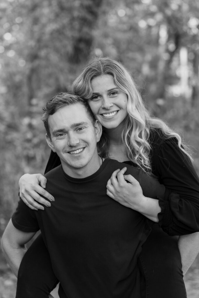 Man giving his girlfriend a piggy back while they both smile at the camera during a couple photography session