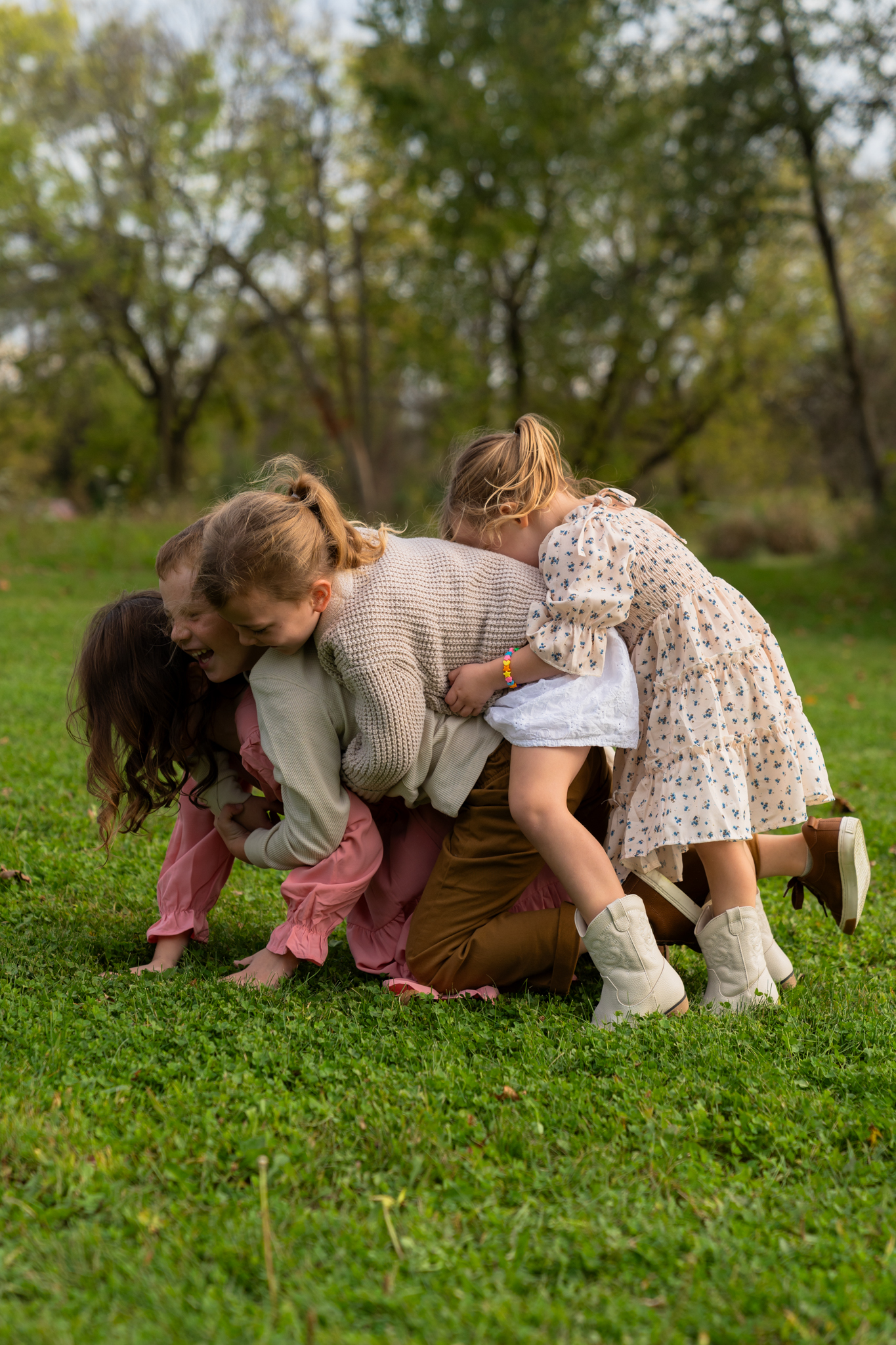 Four young children piled on top of each-other and giggling while playing during family photo session