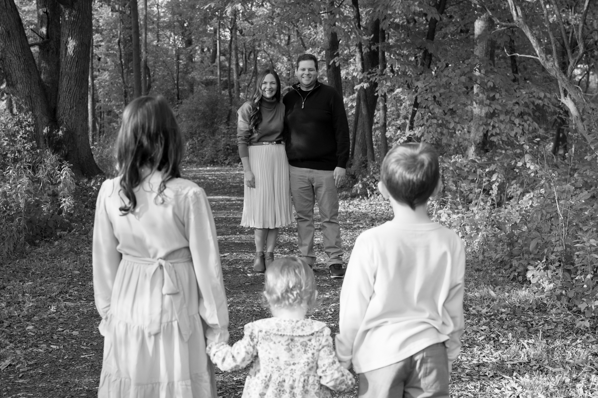 Three children holding hands and looking at their parents during family photoshoot in Lannon Wisconsin