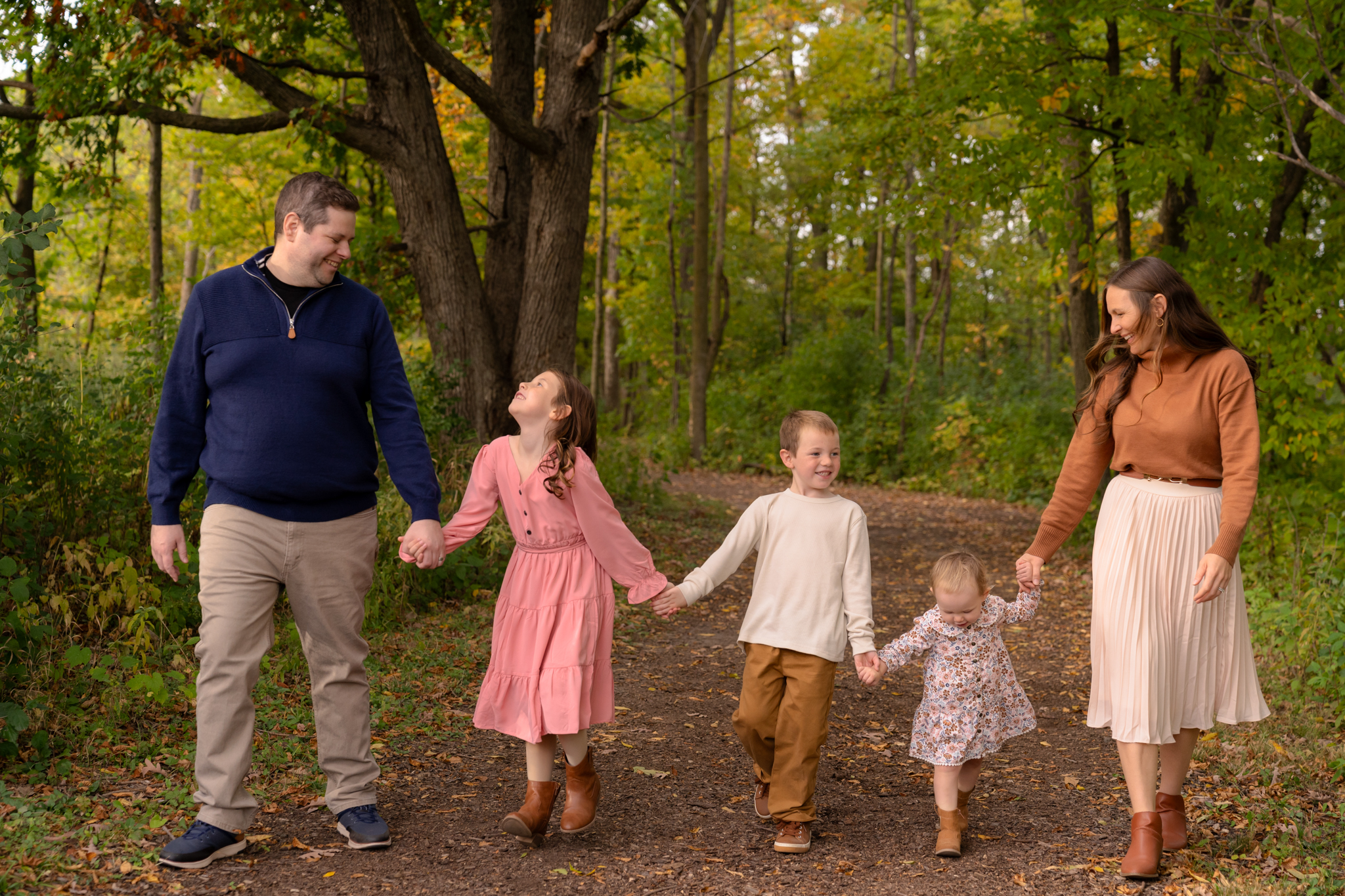 Family of five holding hands and walking through the woods in Menomonee Falls Wisconsin