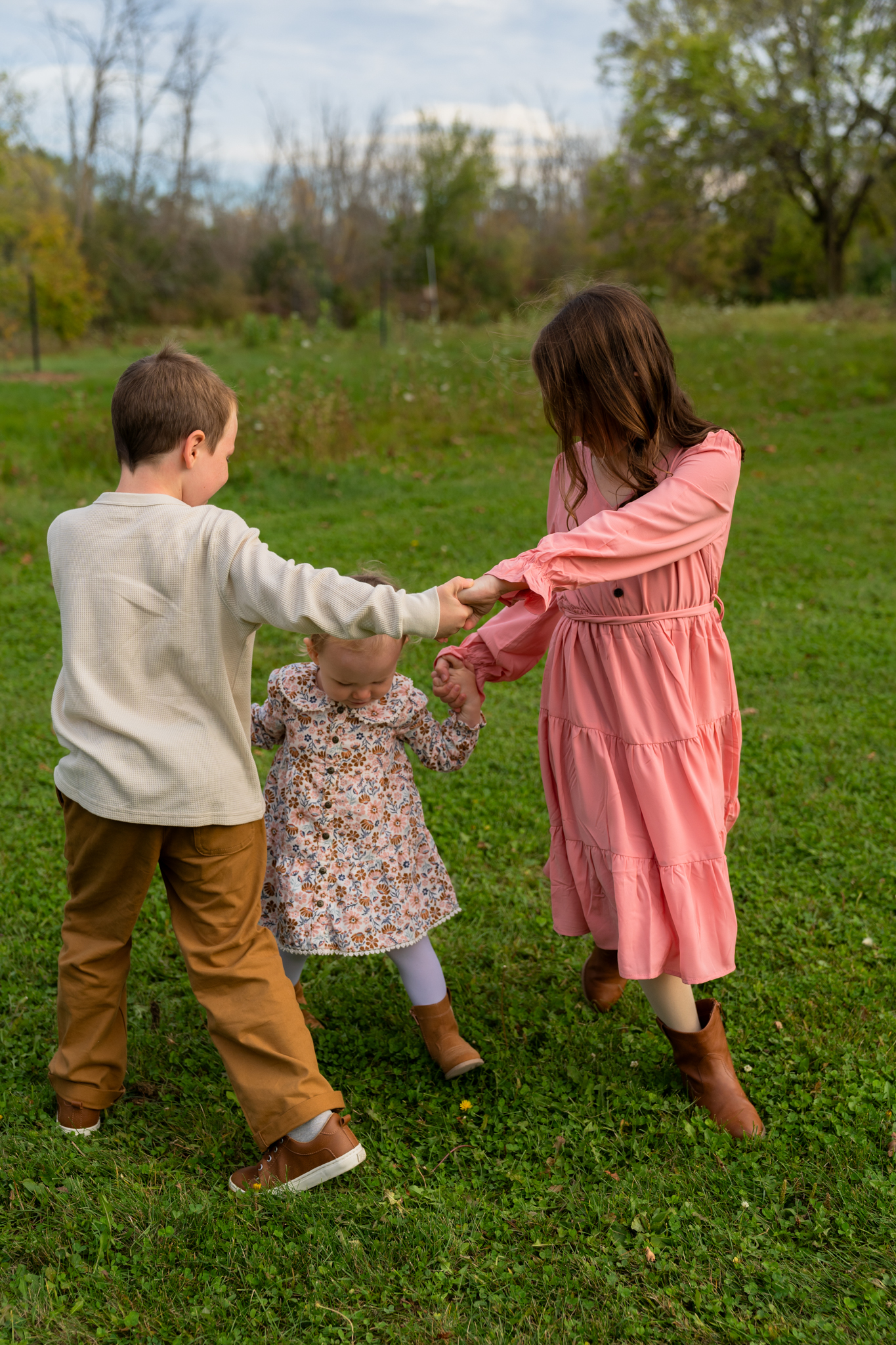 Three siblings playing ring around the rosie at Menomonee Park in Menomonee Falls Wisconsin