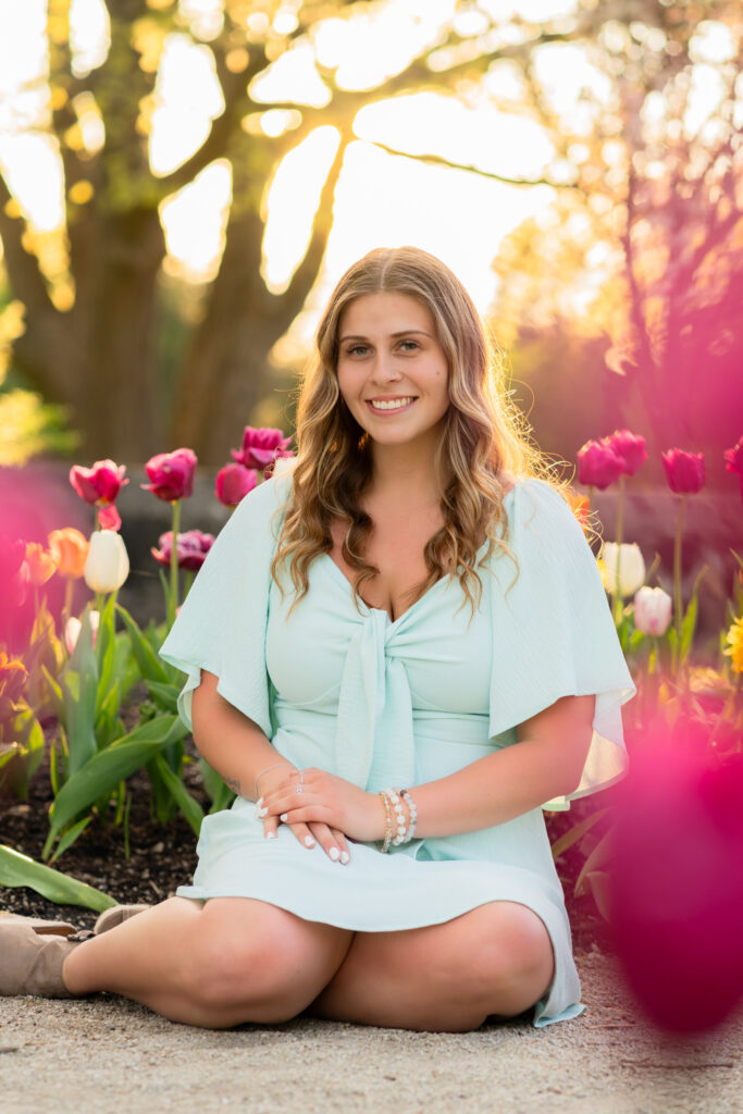 Girl sitting on the ground with tulips surrounding her at Boerner botanical garden in Milwaukee Wisconsin