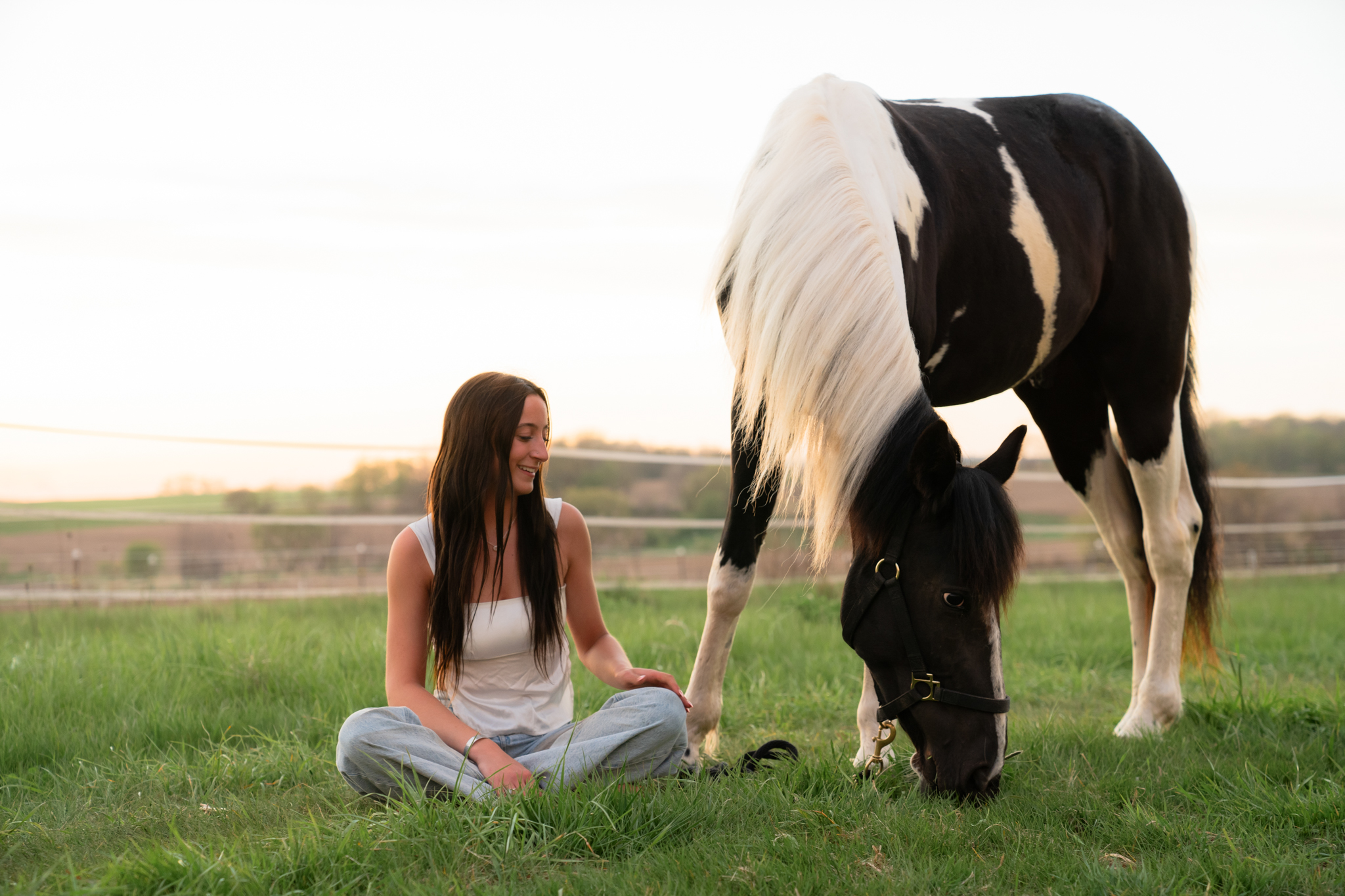 young woman sitting on the ground with horse during Wisconsin equine photography session