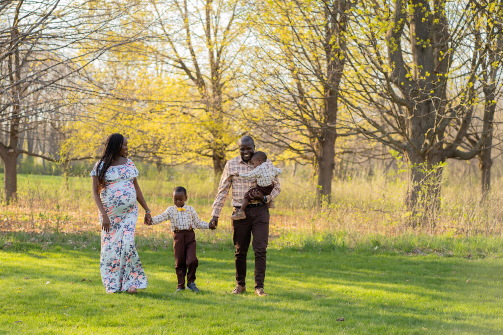 Family of four holding hands and walking together during maternity session in Milwaukee wisconsin