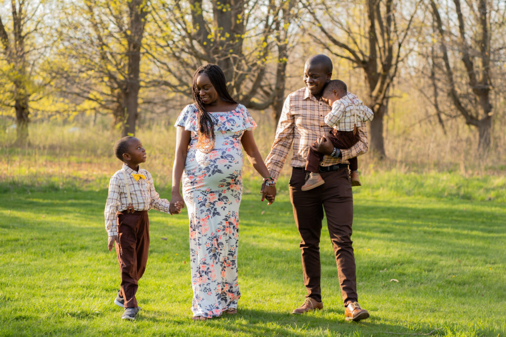 Mom and dad walking candidly with their two boys during maternity session at whitnall park