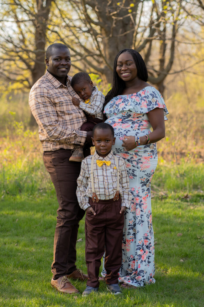 Family of four smiling at the family photographer during maternity session