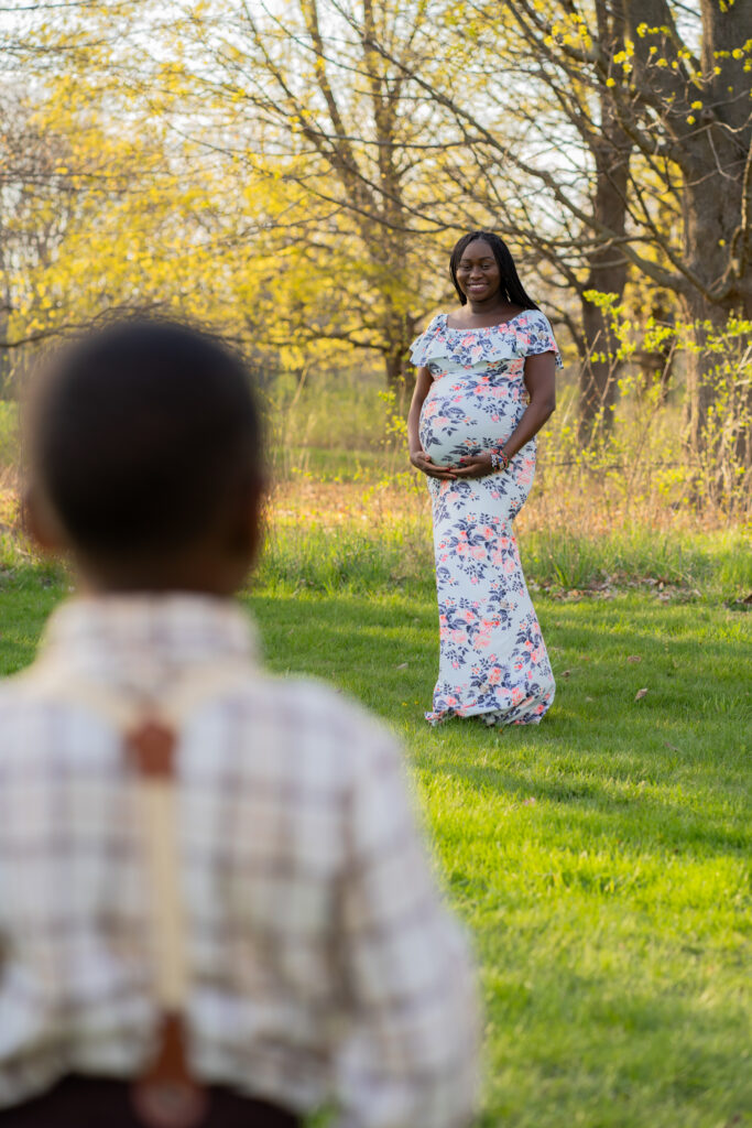 Little boy looking at his mom while she smiles at him during sunset maternity photoshoot