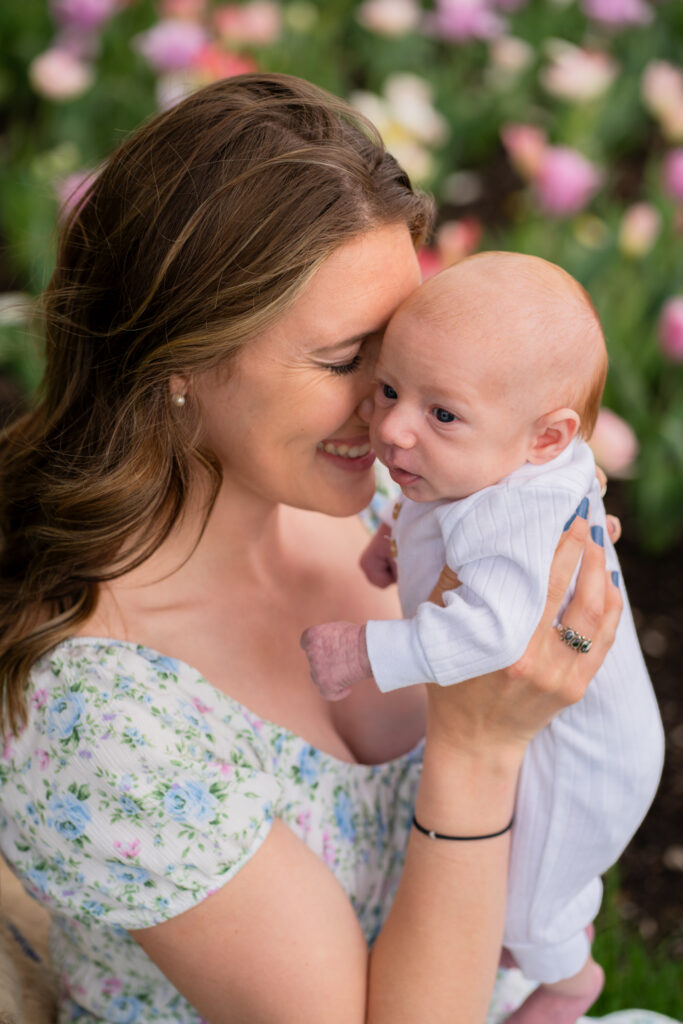 Mother holding her newborn baby and smiling candidly at him during photography session at whitnall park