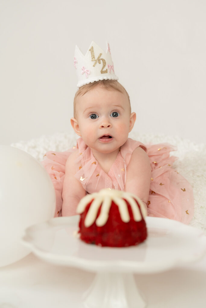 little girl looking at the camera with a birthday hat and cupcake during milestone photography session in cedarburg