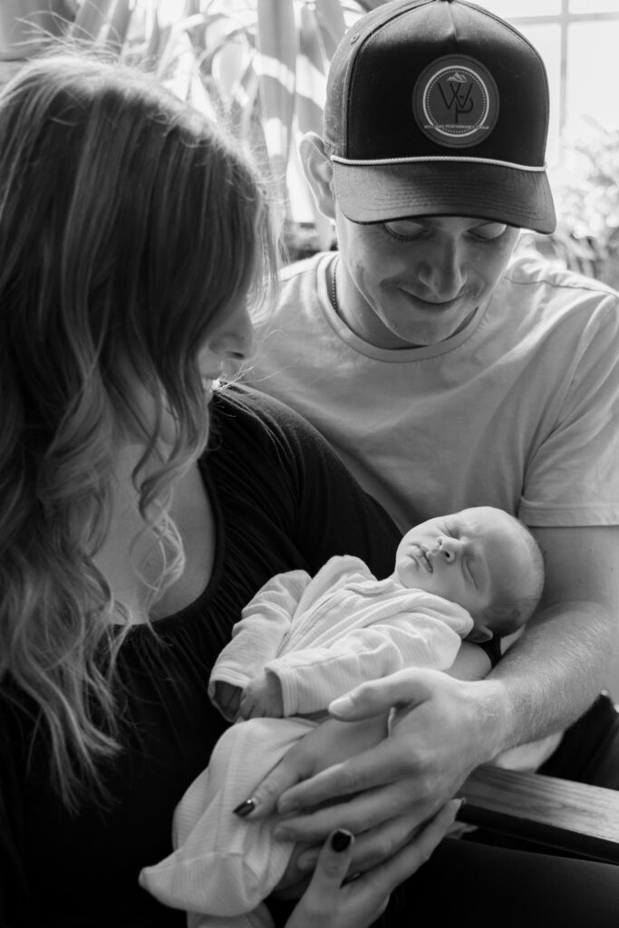 newborn baby in the arms of mother and father during newborn photography session