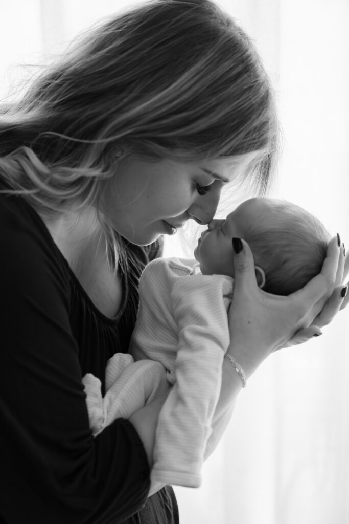 mother and newborn baby touching noses during in home newborn photography session