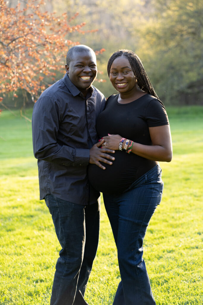 Expecting parents standing together smiling and holding their hands on the mothers belly
