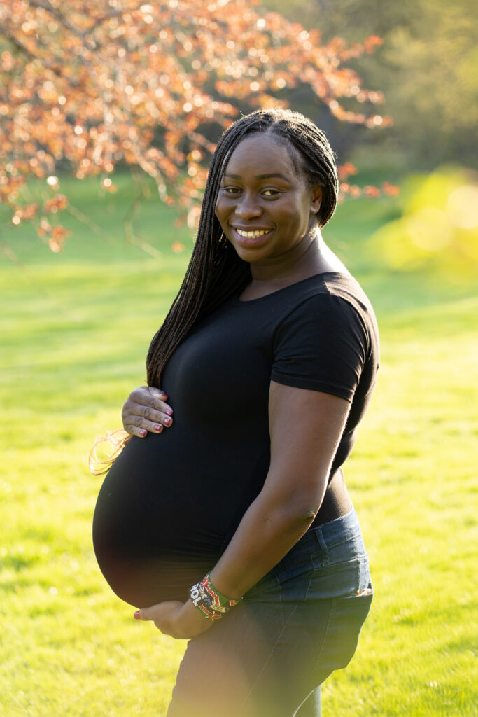 Mother holding her pregnant belly and smiling at the photographer during her maternity photography session in milwaukee wisconsin